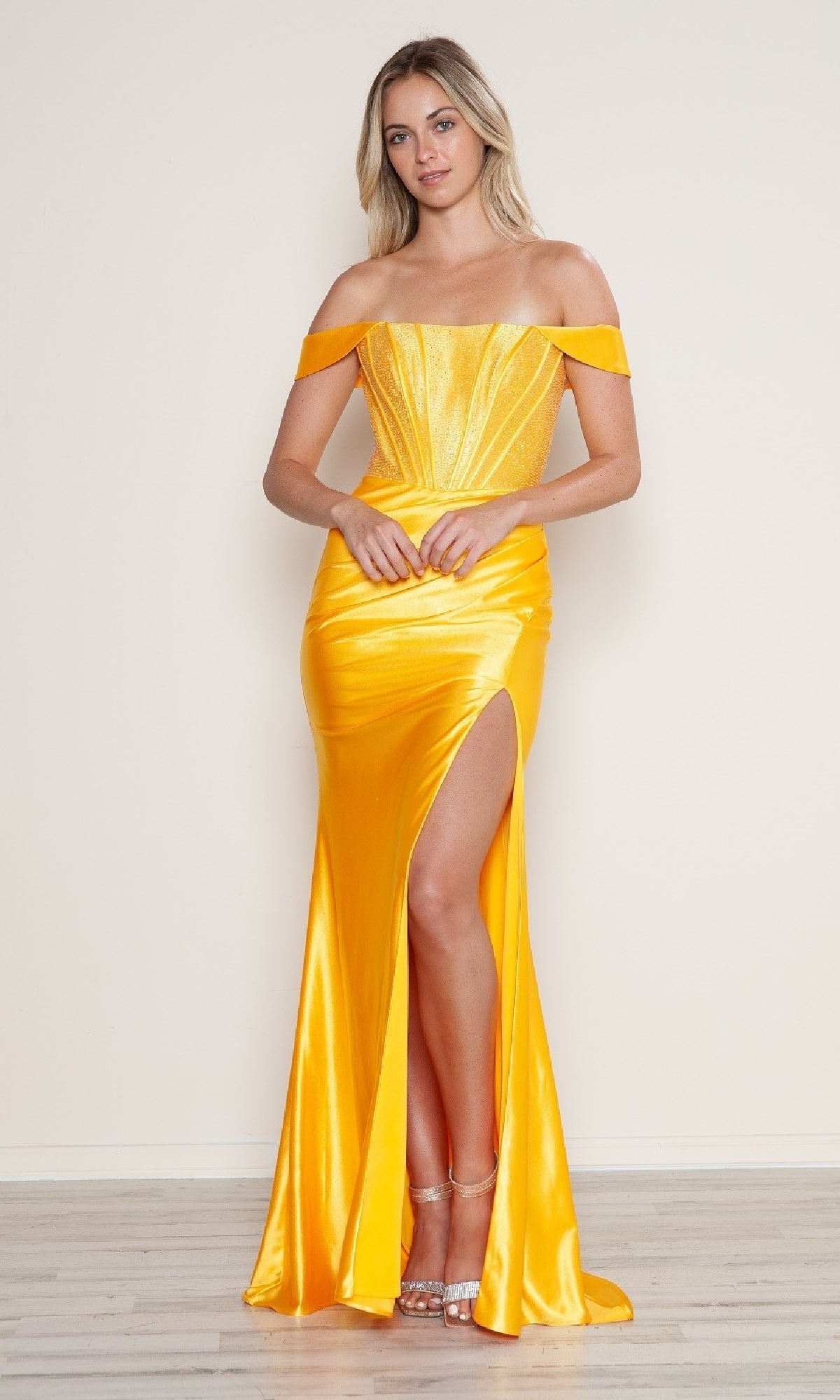 Woman models the Off-Shoulder Long Corset Prom Dress (Poly USA 9656), a bright yellow satin evening gown with a thigh-high slit and strappy heels, against a plain light background.